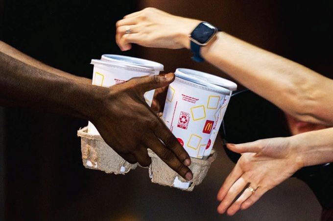 A McDonald's employee hands a customer her food at a drive-thru