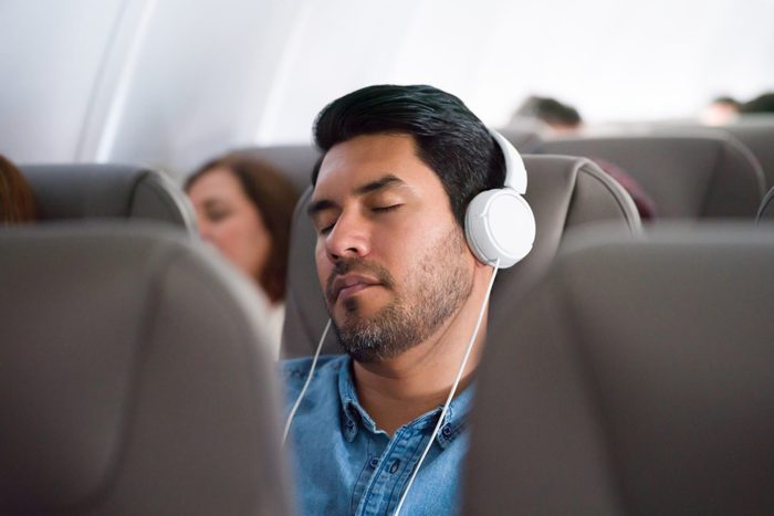Man traveling by plane and listening to music and sleeping