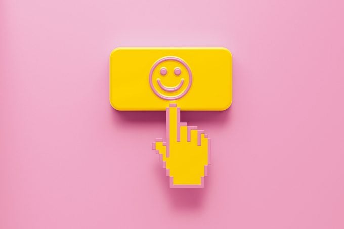 hand clicking on a button with a happy face on a pink background