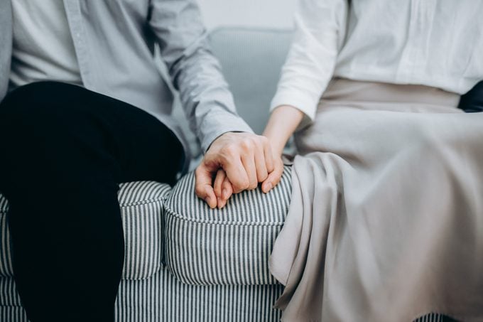 Cropped shot of a a couple sitting on sofa holding hands for comfort