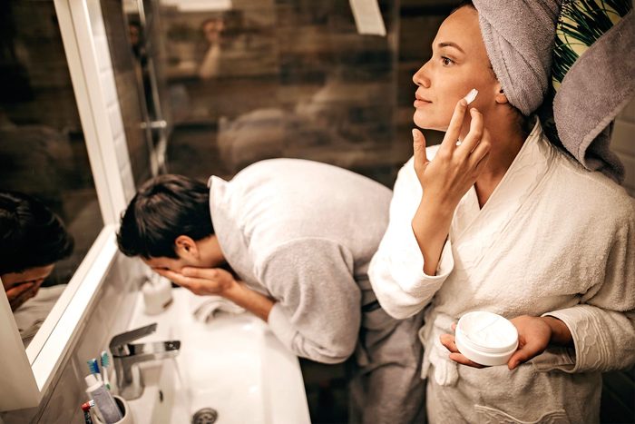 Couple applying skincare and washing face in bathroom