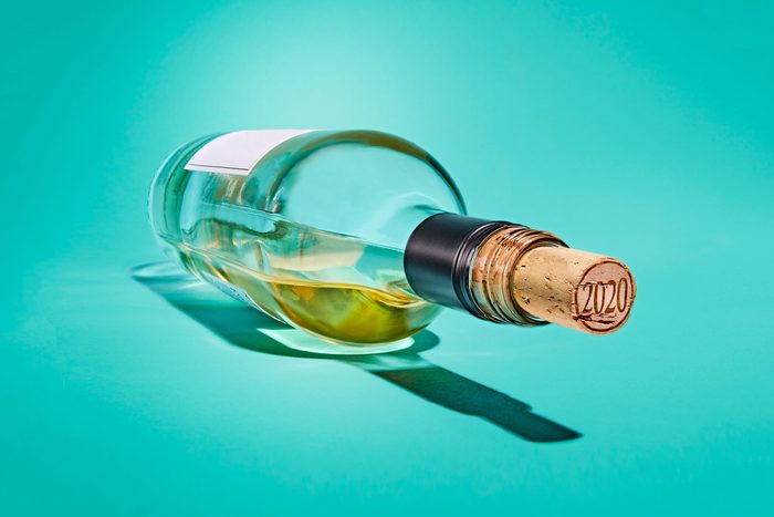 Open bottle of white wine on a teal background