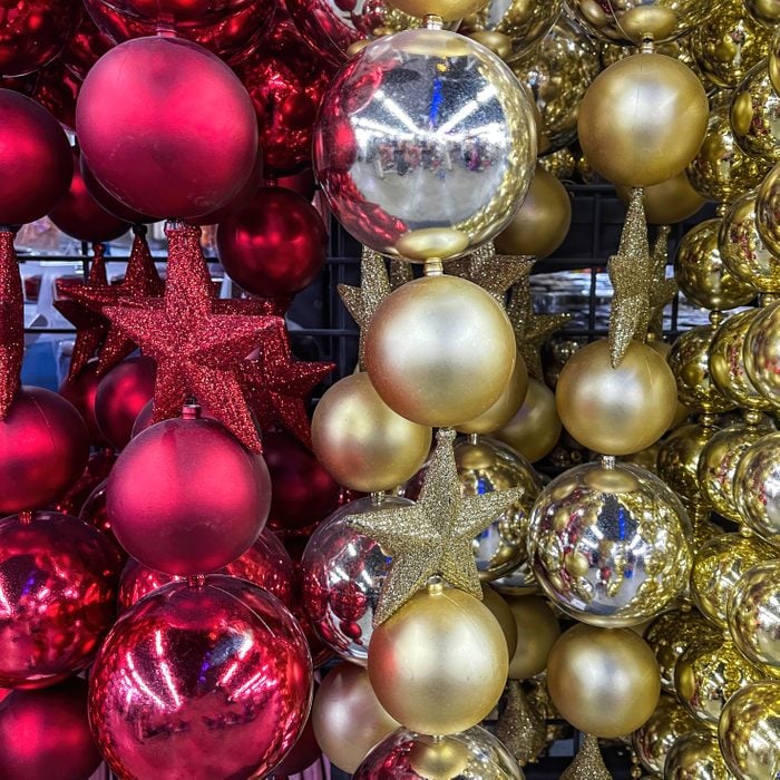 maroon christmas tree balls and red or dark pink star ornaments hung in a christmas decoration store