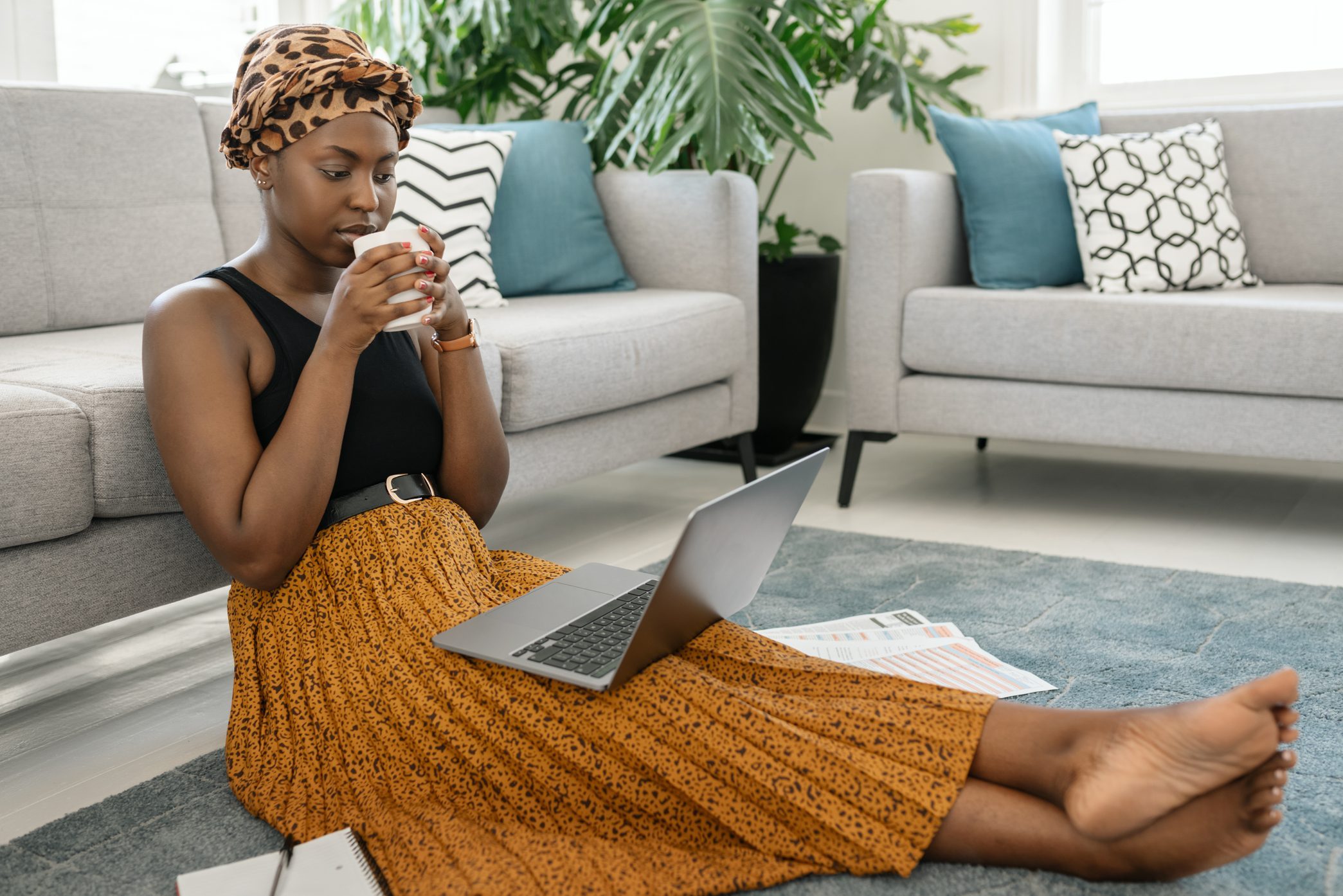 Black African woman on working online on laptop in lounge at home