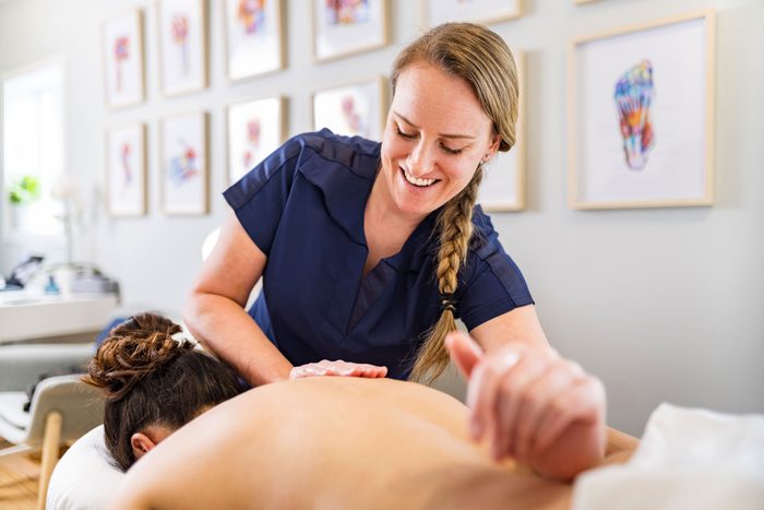 Female massage therapist treating female patient