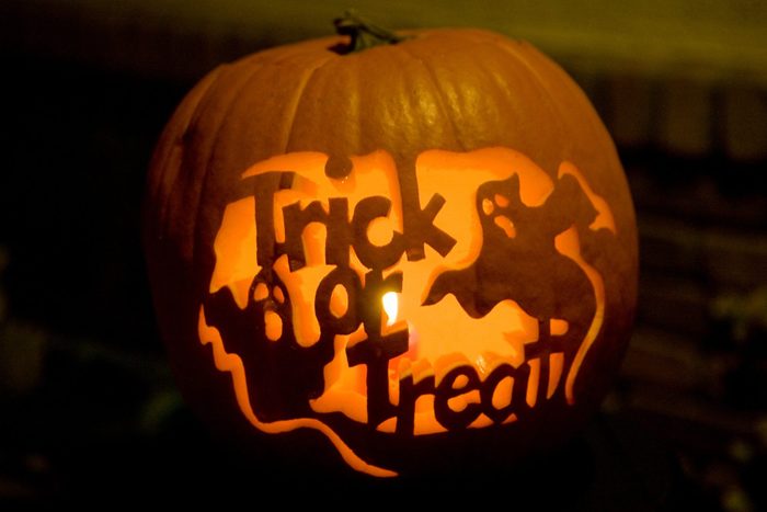 A pumpkin carving in the shape of ghosts and the words "Trick or Treat"