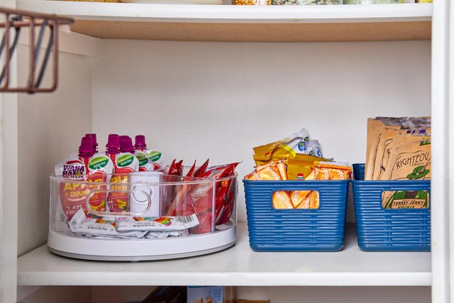 lazy susan and baskets used to organize food and snacks in a kitchen pantry