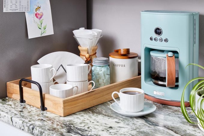 coffee bar in a kitchen with a coffee maker and a tray with mugs, coffee, and tea