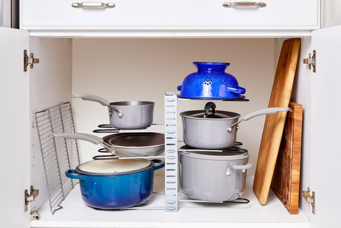 pots and pans in a tall, tiered organizer in a cabinet
