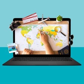 Laptop on a blue background with an image of a map and travel planning tools on the screen