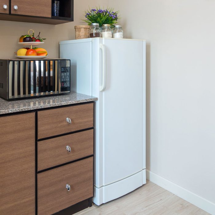 A White Fridge With Spice Jars On Top Of It In A Small Kitchen