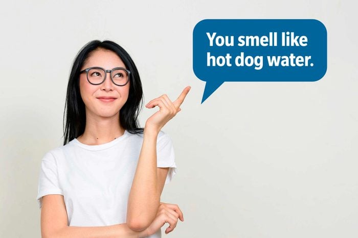 Smiling woman pointing up delivering a comeback roast, speech bubble text: "You smell like hot dog water."