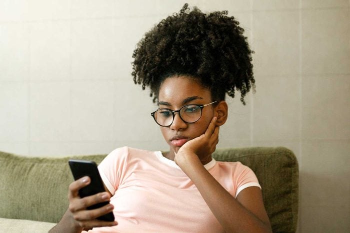 Teenage Girl Using Smart Phone On Couch