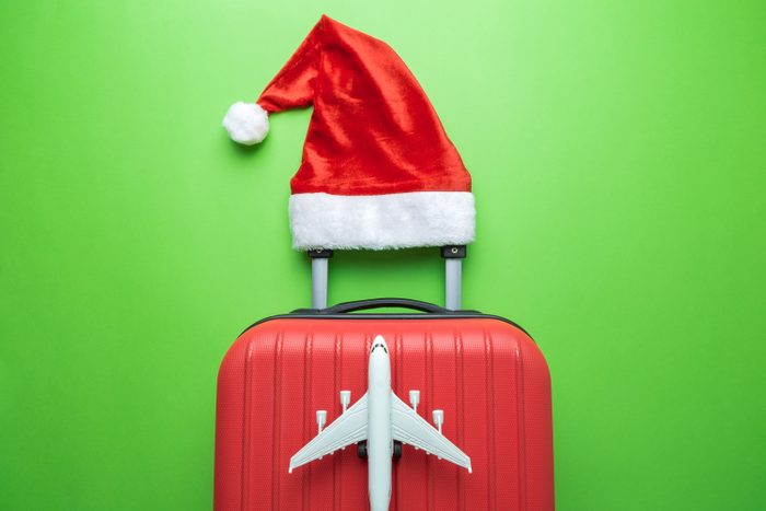 Suitcase With Santa Hat And Airplane Model On Green Background Minimal Creative Christmas Holiday Travel Concept