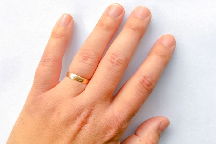 Man's Left Hand With a Gold Wedding Band Isolated on a Bright White Background