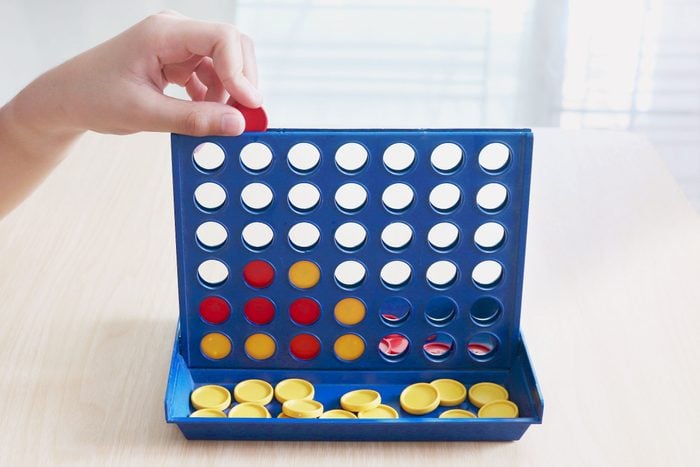 Hand playing Connect Four board game on a wooden table