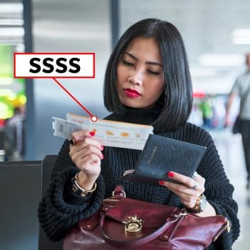 woman looking at a boarding pass at an airport with "SSSS"