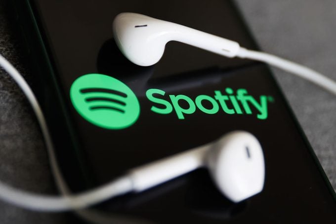 Spotify logo displayed on a phone screen and headphones are seen in this illustration photo