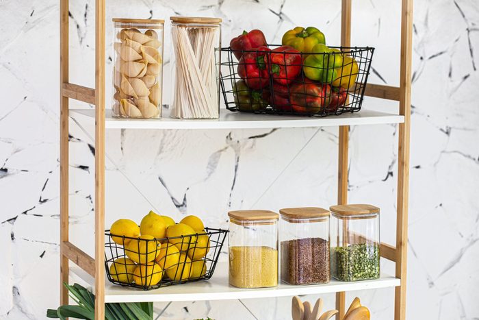 Minimalist pantry rack with fresh lemons, peppers, and glass containers filled with pasta and grains