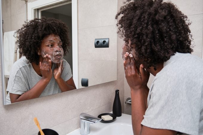 African woman maintains her beauty with daily face washing routine using soap.