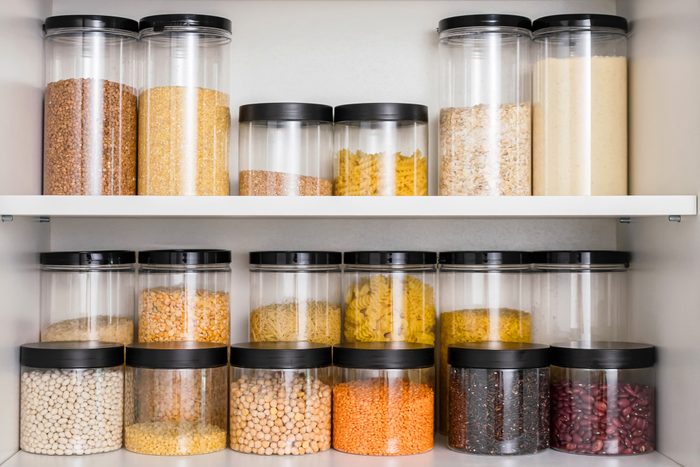 Stored containers with grains and pasta in kitchen cabinet