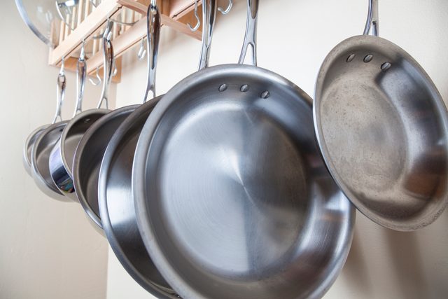 pots and pans hanging on a wall rack in a kitchen