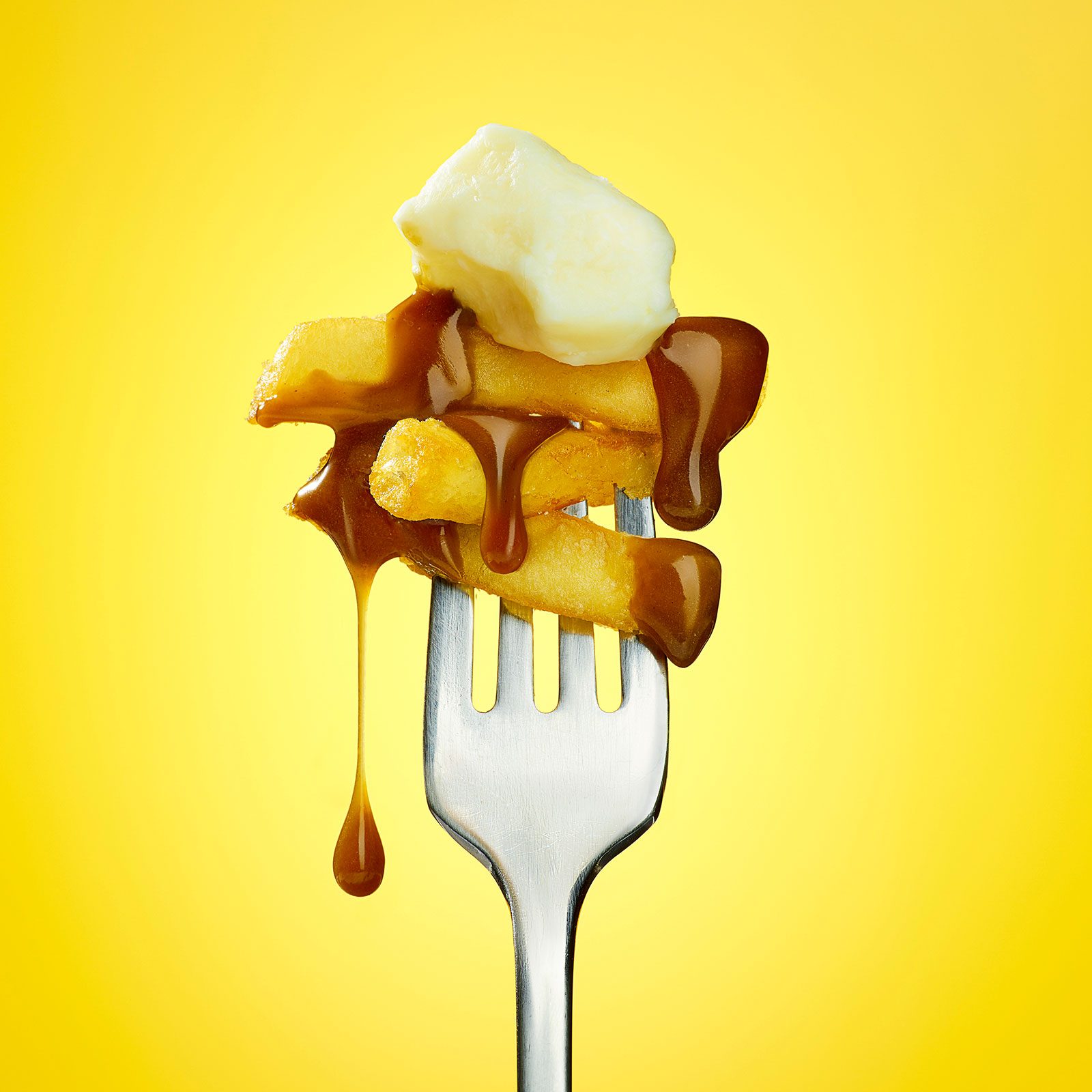 A forkful of poutine, dripping gravy