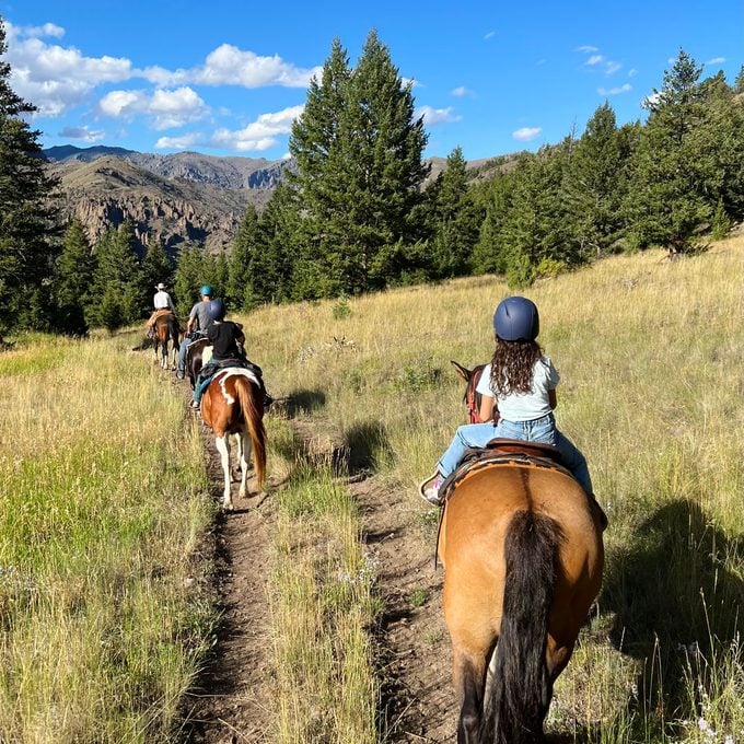 author Anne Fritz's family riding on horseback through yellowstone national park