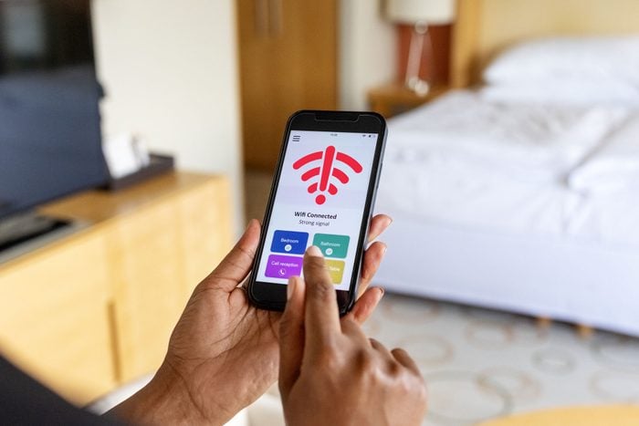 Close Up Of A woman's hand Connecting To The Mobile Wifi In Hotel Room, the screen shows the wifi icon with an exclamation point alert symbol