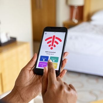Close Up Of A woman's hand Connecting To The Mobile Wifi In Hotel Room, the screen shows the wifi icon with an exclamation point alert symbol