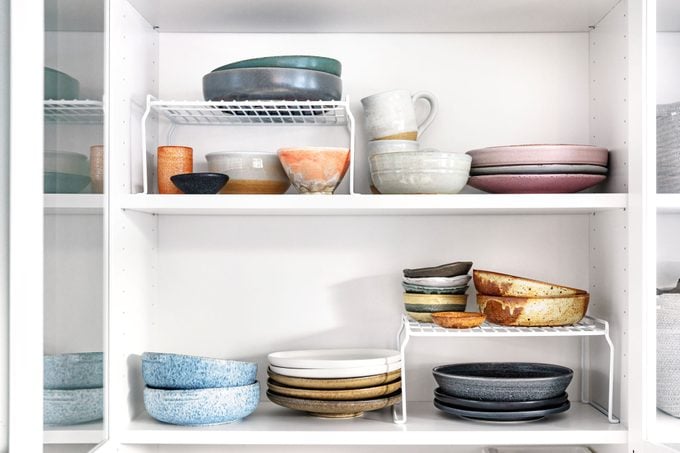 organized cabinet full of plates, bowls, tableware with shelf risers