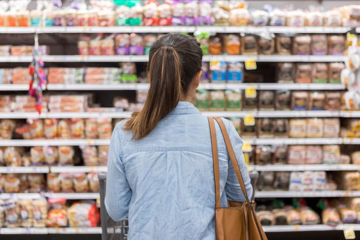 Unrecognizable Woman Marvels At Grocery Store Bread Selection in Bread Aisle
