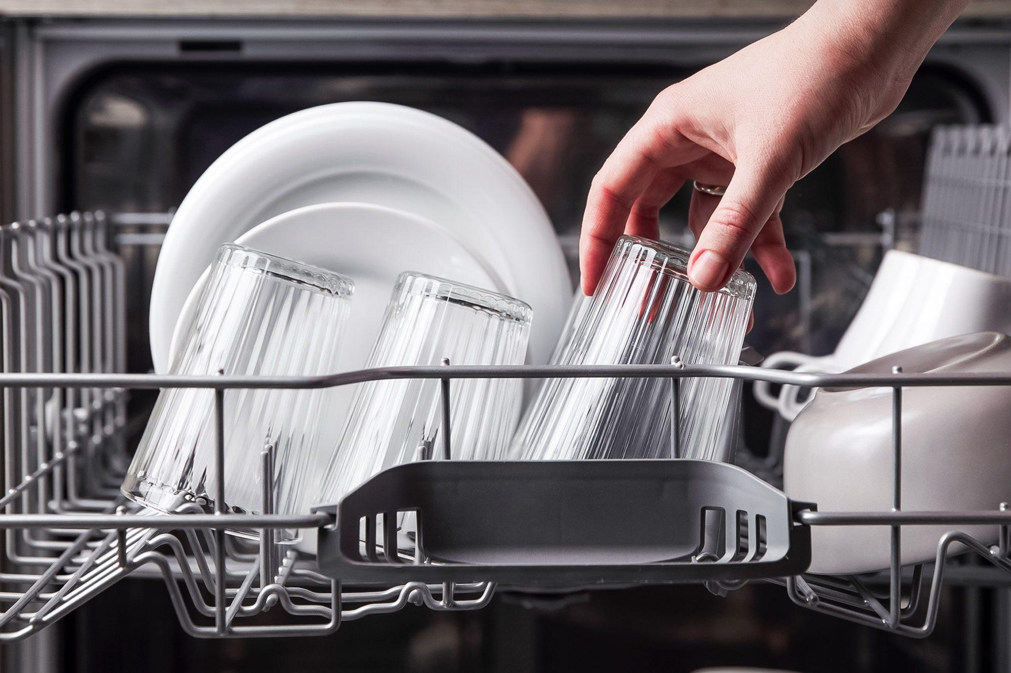 Close Up Of Female Hand Loading Glasses In Dishwasher