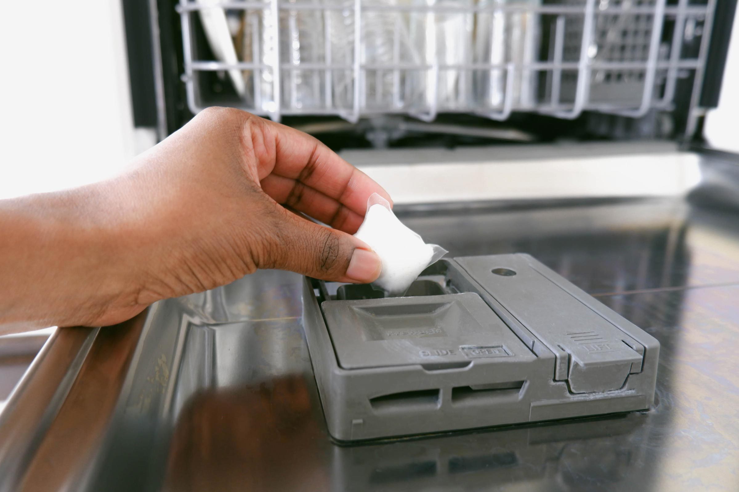 hand putting dishwasher pod in dishwasher