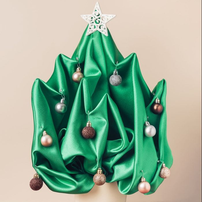 Christmas tree made of green shiny satin fabric, branches hanging in the air,