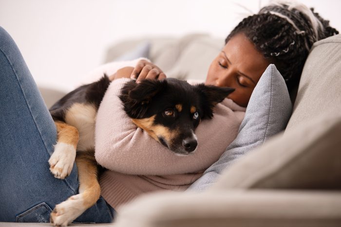 dog comforting sad woman on couch