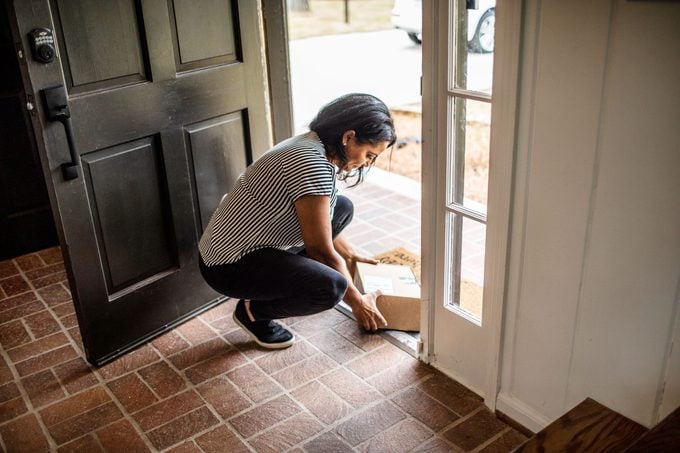 woman taking package inside her front door