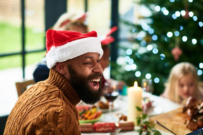 Candid portrait of mid adult black man wearing Santa hat laughing