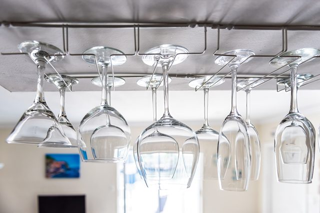 Closeup of modern kitchen interior design with upside down hanging empty wine glasses rack in room for storage