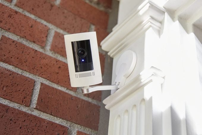 A outdoor home security smart home technology camera looking directly into camera with recording light on.