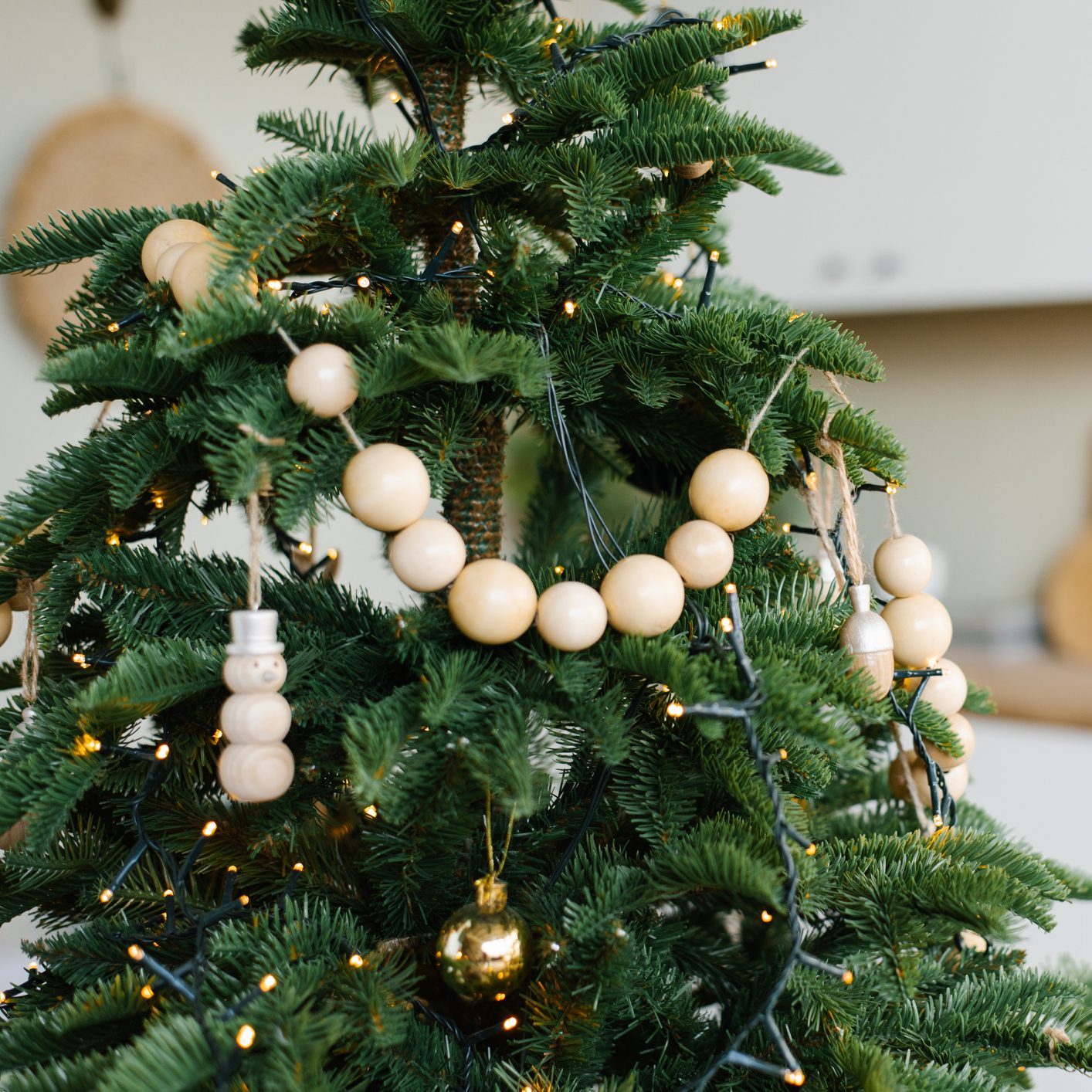 Stylish wooden beads on a Christmas tree in the dining room of a Scandinavian home