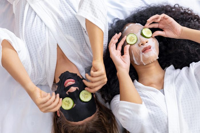 Couple of girlfriend in bathrobe doing skincare routine using facial mask and cucumber slice on spa holiday for beauty skin and treatment concept