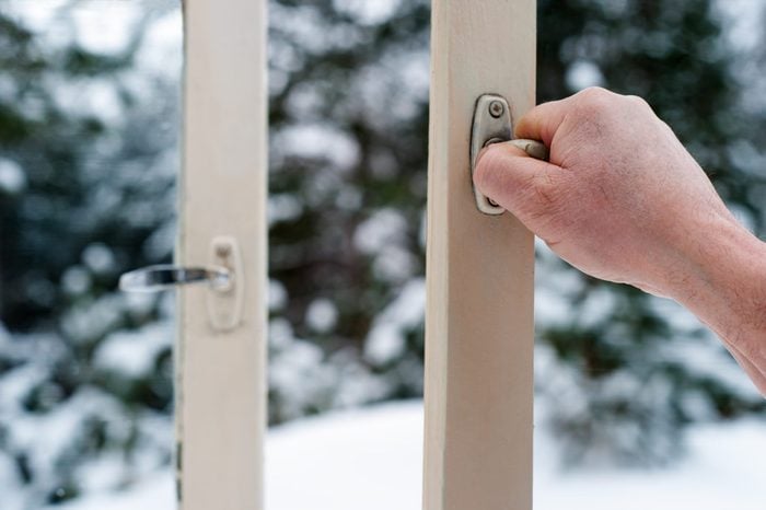 Man's Hand Opens A Wooden Window Against a Snowy Forested Wooded Background