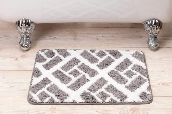 Gray and White Patterned Bathmat in Front of a Silver and White Clawfoot Bathtub