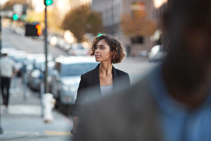 woman looking around while walking in a city. obscured figure in the foreground