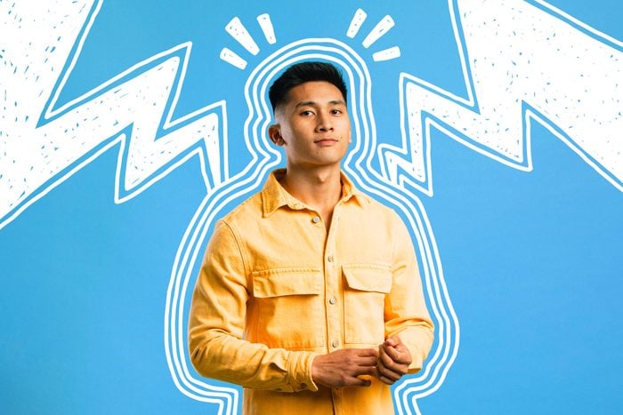 A confident young Asian man standing in front of a blue background, doodles