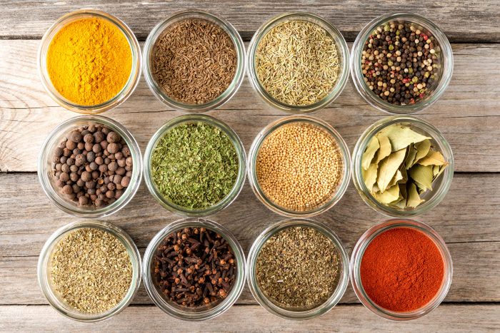 Collection of Various Kinds Of Colourful Seasonings In Jars on a wooden table background