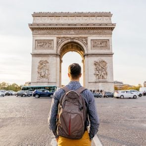 Tourist With Backpack Walking Towards Arc De Triomphe In Paris France