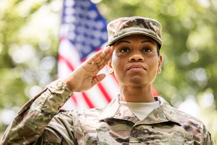 Female U.S. soldier wearing 2023 OCP uniform saluting in front of american flag