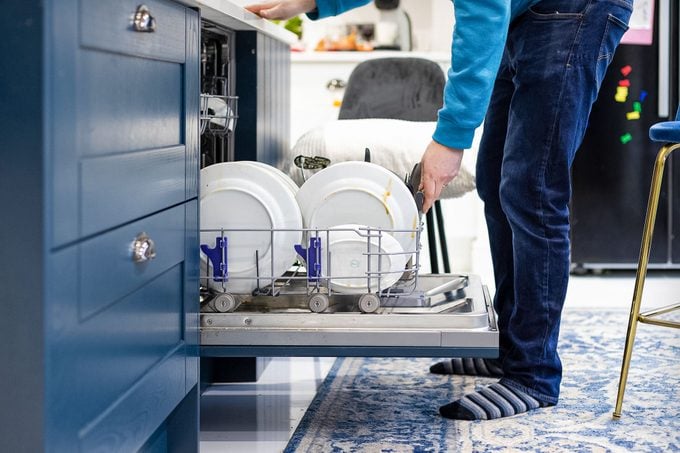 A Man Filling Up Dishwasher With Dirty Plates